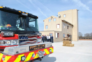 Truck in foreground with students receiving a briefing in the background. 